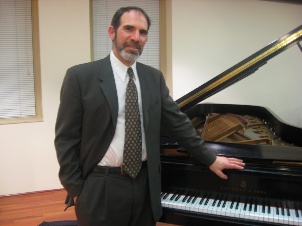 Robert Sykes standing at a piano.